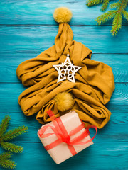 Christmas winter flat lay with yellow scarf tree and wrapped gift box on green wooden background