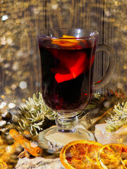 Christmas mulled wine with spices in glasswith plaid and snow on a christmas tree on dark background, The glass cup of hot winter drink