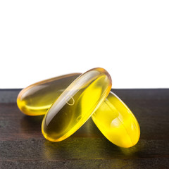 Yellow capsules omega 3, fatty acid, fish oil on dark wooden table, macro image