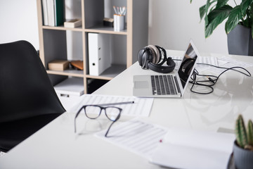 Close up of papers with musical notes, laptop and earphones on desk in office