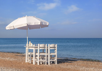 Fototapeta premium White wooden table on beach with blue sea with four chair and umbrella