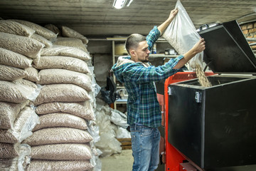 the man loads the pellets in the solid fuel boiler, economical heating