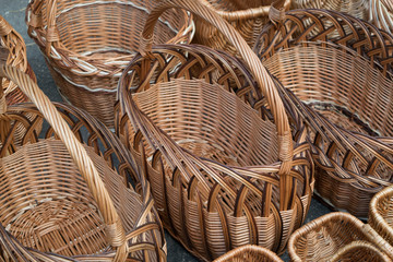 Several rows of wicker baskets. Basket woven of twigs. Patterns of waves and braids. Baskets with handles of different shapes. Basket for fruit or fungi, or for a hike in the store.