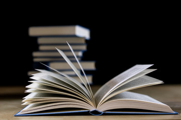 Heap of books reading on a wooden table. Beside lies . Black background.