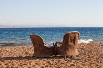 couple of old arm chairs   on a sand beach. Eilat. Israel