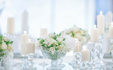 Fashionable decoration of a wedding banquet with white flowers. On the table are crystal vases with floral compositions