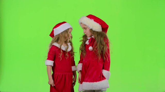 Two children girls swear and argue, they are in colorful costumes. Green screen