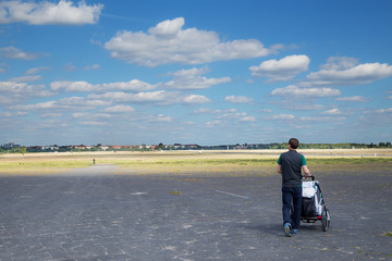 Young male tourist visiting Tempelhofer Feld in Berlin with a stroller and his child