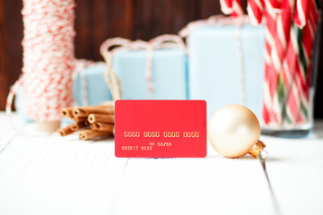 Christmas composition New Year selling discount concept red credit card  with xmas gifts sweets toys balls rope cinnamon on white wooden table and brown background