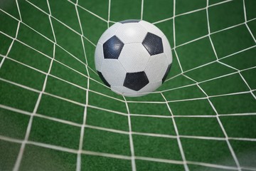 Fototapeta na wymiar Football in goalpost against artificial grass