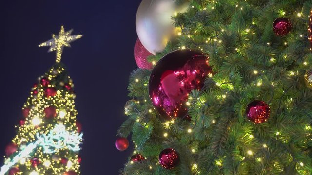 Greeting Season concept. Gimbal shot of ornaments on a Big Christmas tree with decorative light and falling snow in 4k (UHD)