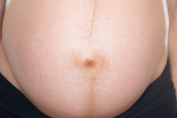 Macro shot of Linea Nigra and bellybutton on the belly of a pregnant woman