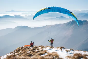 Fototapeten taking picture to a paraglider takeoff on the mountain. Italian Alps © ueuaphoto