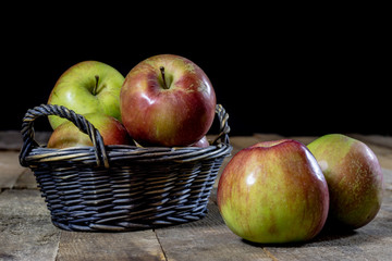 Tasty apples in basket on kitchen table. Autumn season. Wooden table.
