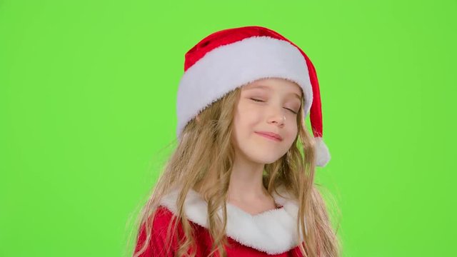 Baby girl in red Christmas caps send air kisses. Green screen