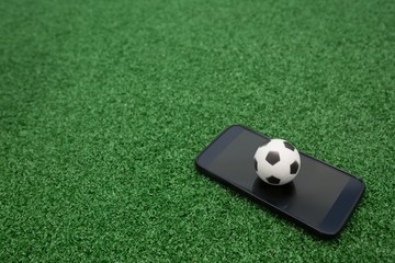 Naklejka premium Football and mobile phone on artificial grass