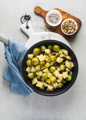 Italian gnocchi from potatoes with Brussels sprouts and walnuts in a frying pan on a white marble cutting board on a stone kitchen table. classic healthy recipes