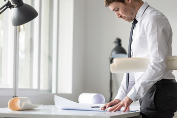 Businessman or arhitect in white shirt using ruler and pencil while working at the plan