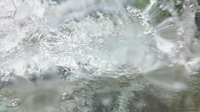 SLOW MOTION CLOSE UP: Frisky black dog dives into river water to return yellow ball and splashes water into camera lens. Young dog with wet coat jumps into deep stream to cool off in sunny weather.