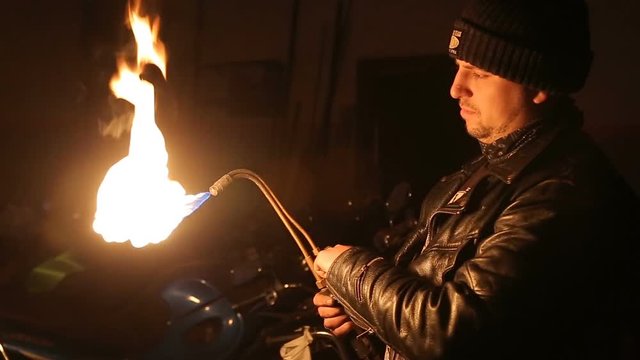 Auto mechanic lights the autogenous before reparing motorcycle