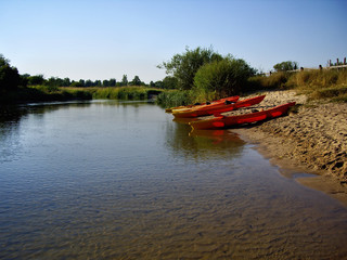 Fototapeta na wymiar czerwone kajaki na piaszczystym brzegu rzeki