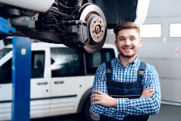 A young man works at a service station. The mechanic is engaged in repairing the car.