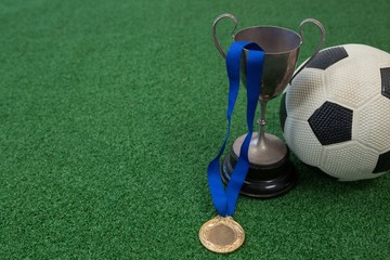 Football, trophy and medal on artificial grass
