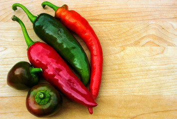 Variety of fresh peppers isolated on wooden table with copy space