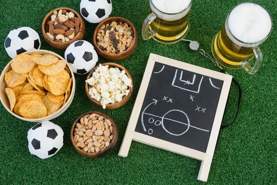 Strategy board, football and snacks on artificial grass