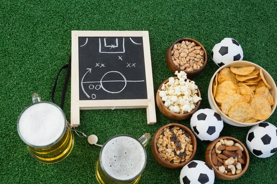 Strategy board, football and snacks on artificial grass