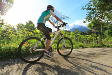 Fototapeta na wymiar young woman cyclist cycling on sunrise forest trail