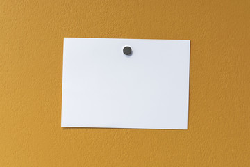 Plain white note paper against a bright yellow wall.