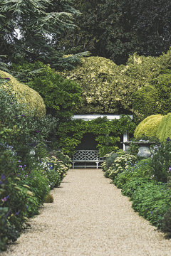 Traditional English country garden path with a bench in the distance.