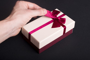 Man's hand unwrapping gift box on black background