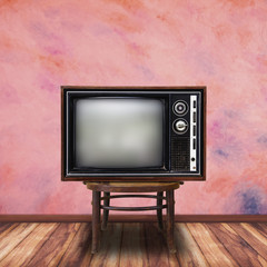 Old television on wood chair in vintage room background.