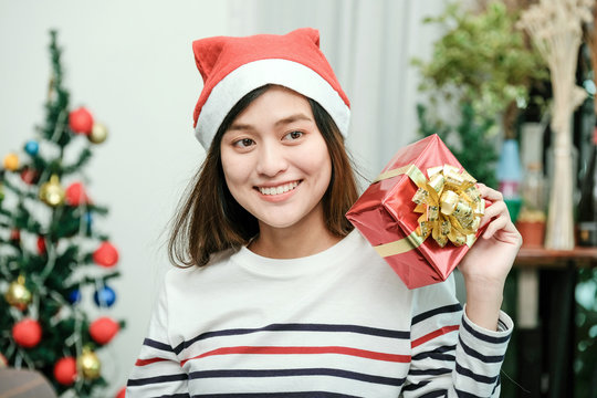 Young cute asia woman smiling and holding red gift box at Christmas party, Christmas people celebration concept