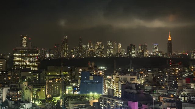 Tokyo city skyline with Shinjuku skyscrapers at night, Japan. Time lapse with rain and clouds rolling