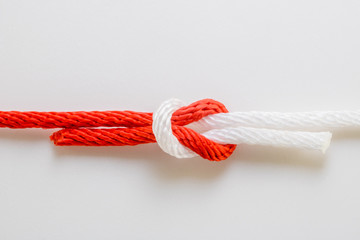 Close up red and white rope reef knot on a white background.