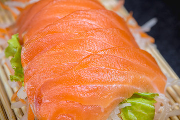 Close up raw fresh salmon sashimi set salad  on black table.