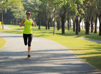 Young fitness woman running at tropical park