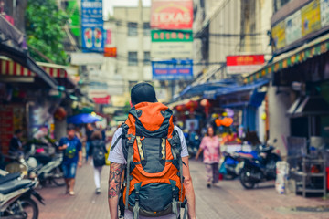 Naklejka premium Backpacker man walking in the street of Asia. Bangkok, Thailand.