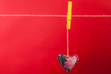 Heart fabric hanging on clothesline and red background with free space