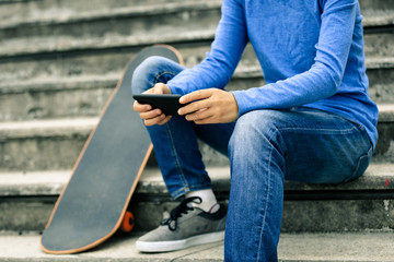 skateboarder use smartphone sit on city stairs