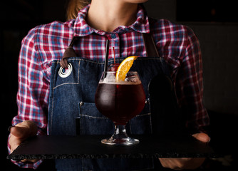 Girl waiter holds an alcoholic cocktail