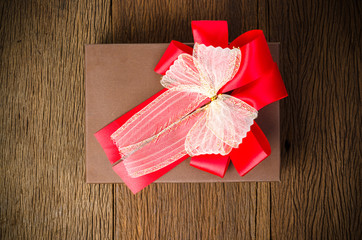 Brown gift box with white and red bow on wooden table background
