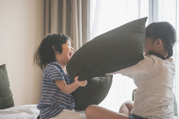 Happy Asian child ren having Pillow Fight in Hotel Room