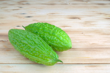 Fresh bitter melon or bitter gourd (Momordica charantia)  over pine wood grain