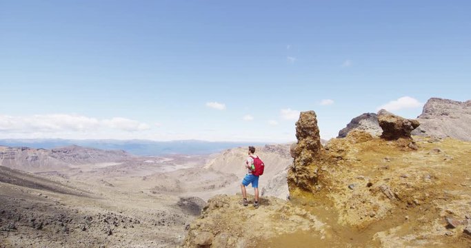 Hiker man looking at view with backpack in spectacular mountain landscape. Active male backpacker is hiking in Tongariro National Park, New Zealand. Man is enjoying the view of beautiful nature.
