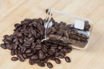 Dry coffee beans in test tube on wood background