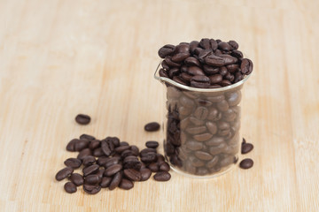 Dry coffee beans in test tube on wood background